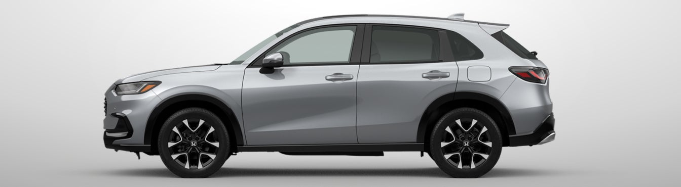 Exterior side view of a 2027 HR-V in Solar Silver Metallic parked agaisnt a light gray background