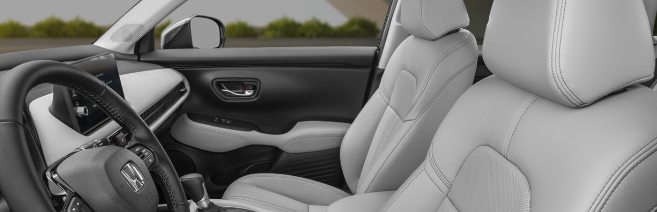 Perspective shot of 2027 Honda HR-V interior in gray perforated leather seen from outside the front driver side window.