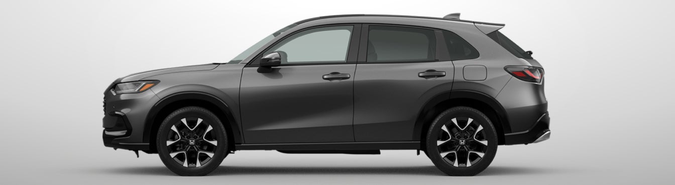 Exterior side view of a 2027 HR-V in Modern Steel Metallic parked agaisnt a light gray background