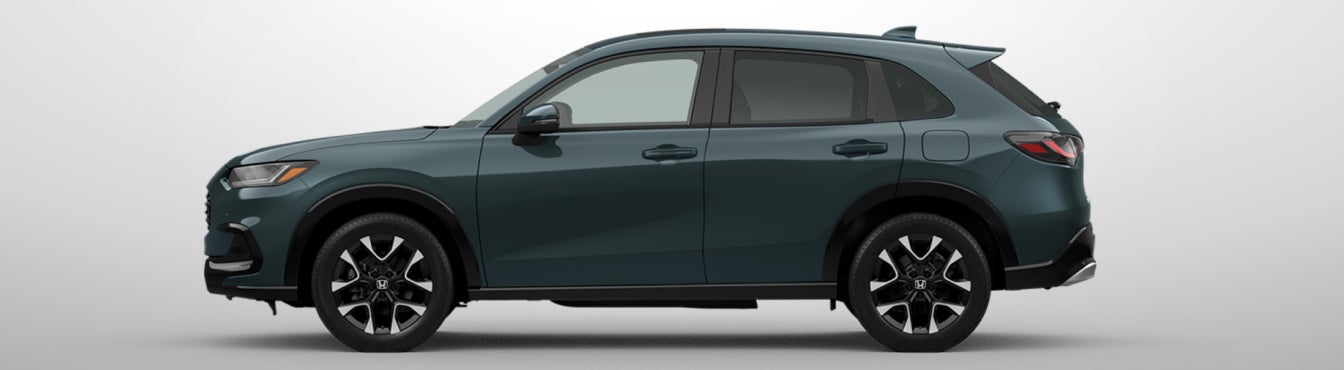 Exterior side view of a 2027 HR-V in Nordic Forest Pearl parked agaisnt a light gray background