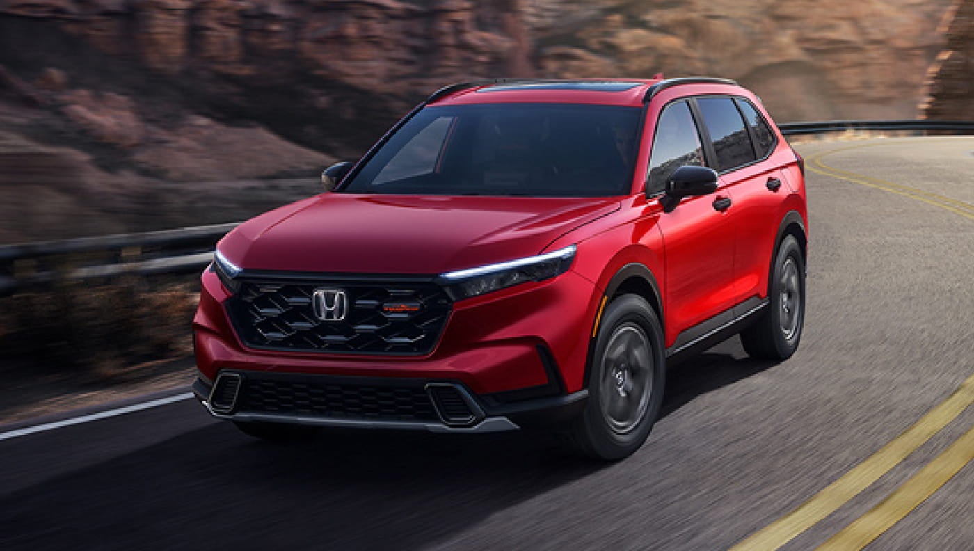 Red Honda CR-V driving on a winding mountain road, shown from the front three-quarter view.
