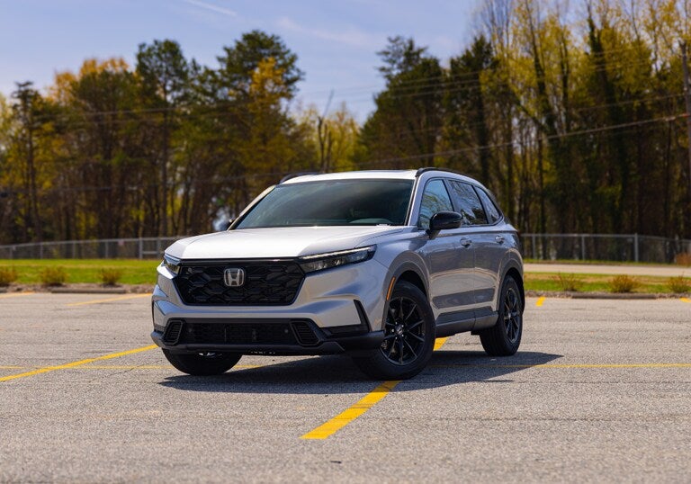 Front view of a 2026 Honda CR-V Hybrid parked in a lot with trees in the background